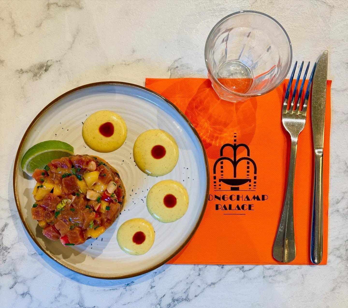 Un tartare aux fruits frais servi sur la serviette orange au logo du Longchamp Palace.
