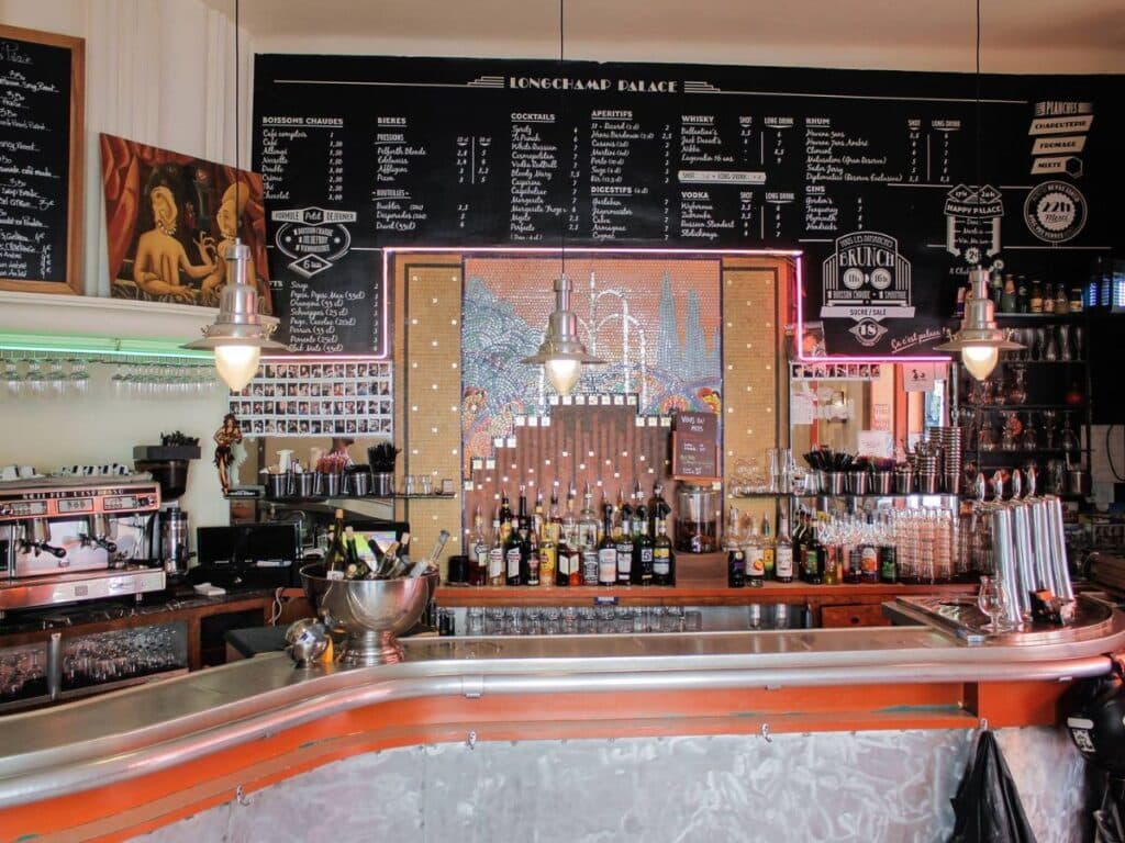 Le comptoir en zinc du Longchamp Palace, les ardoises de la carte et la fresque au centre.
