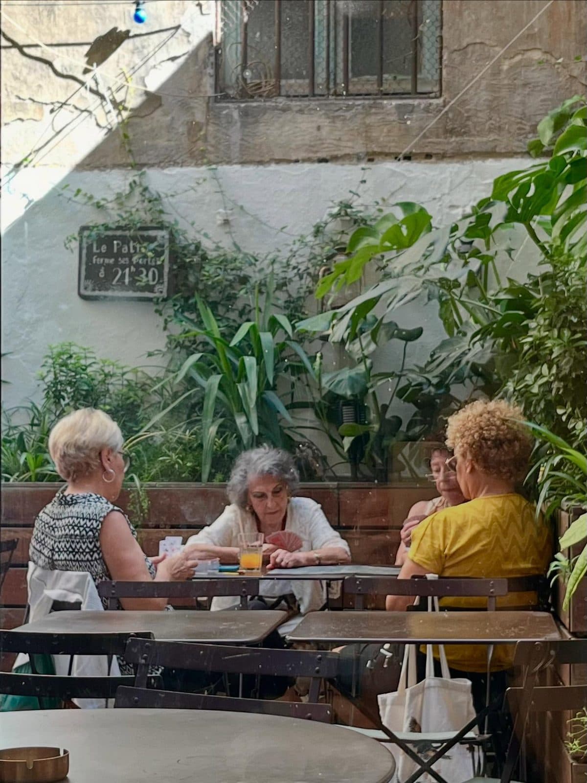 Le patio planté du Longchamp Palace, des habituées attablées autour d’une partie de cartes.